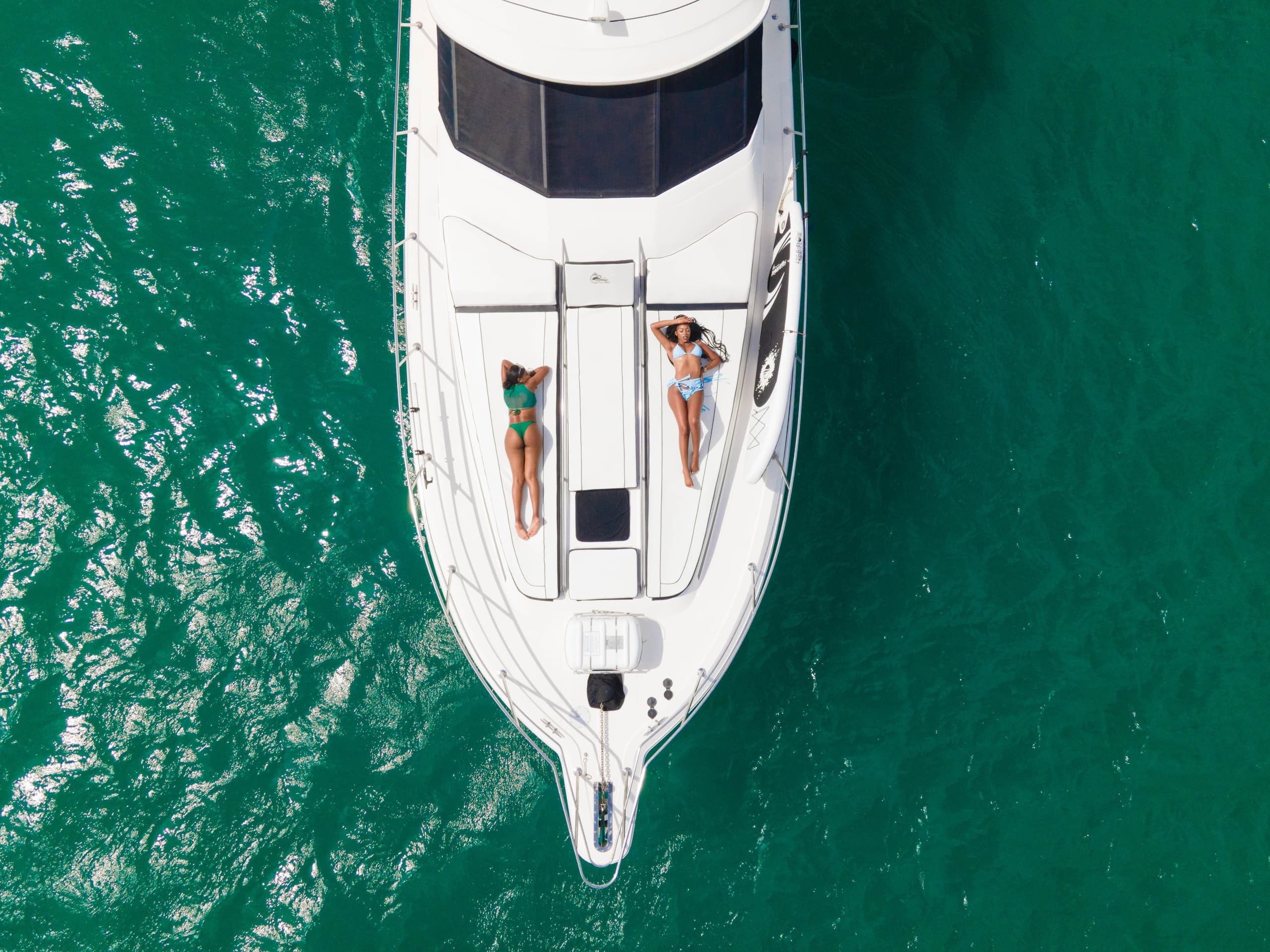 Aerial view of luxury yacht on turquoise ocean with sunbathers