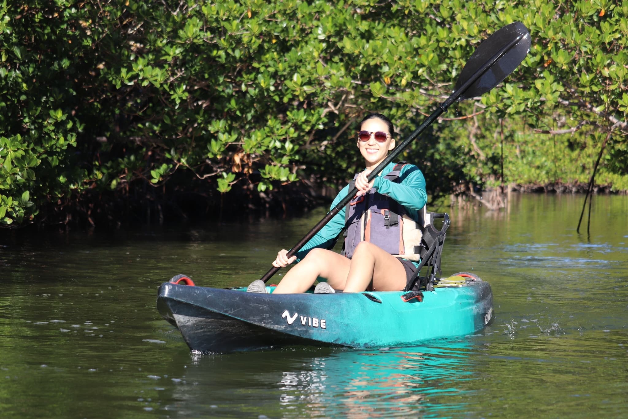 Solo kayaker paddling through mangrove-lined calm waters