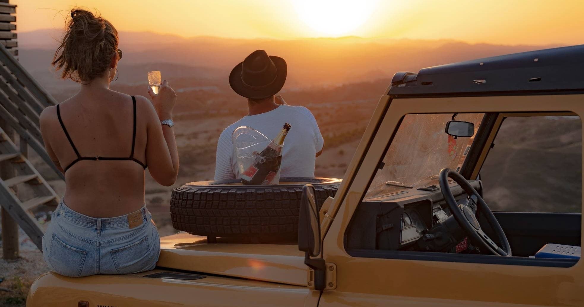 Couple watching sunset from open jeep over Algarve coast