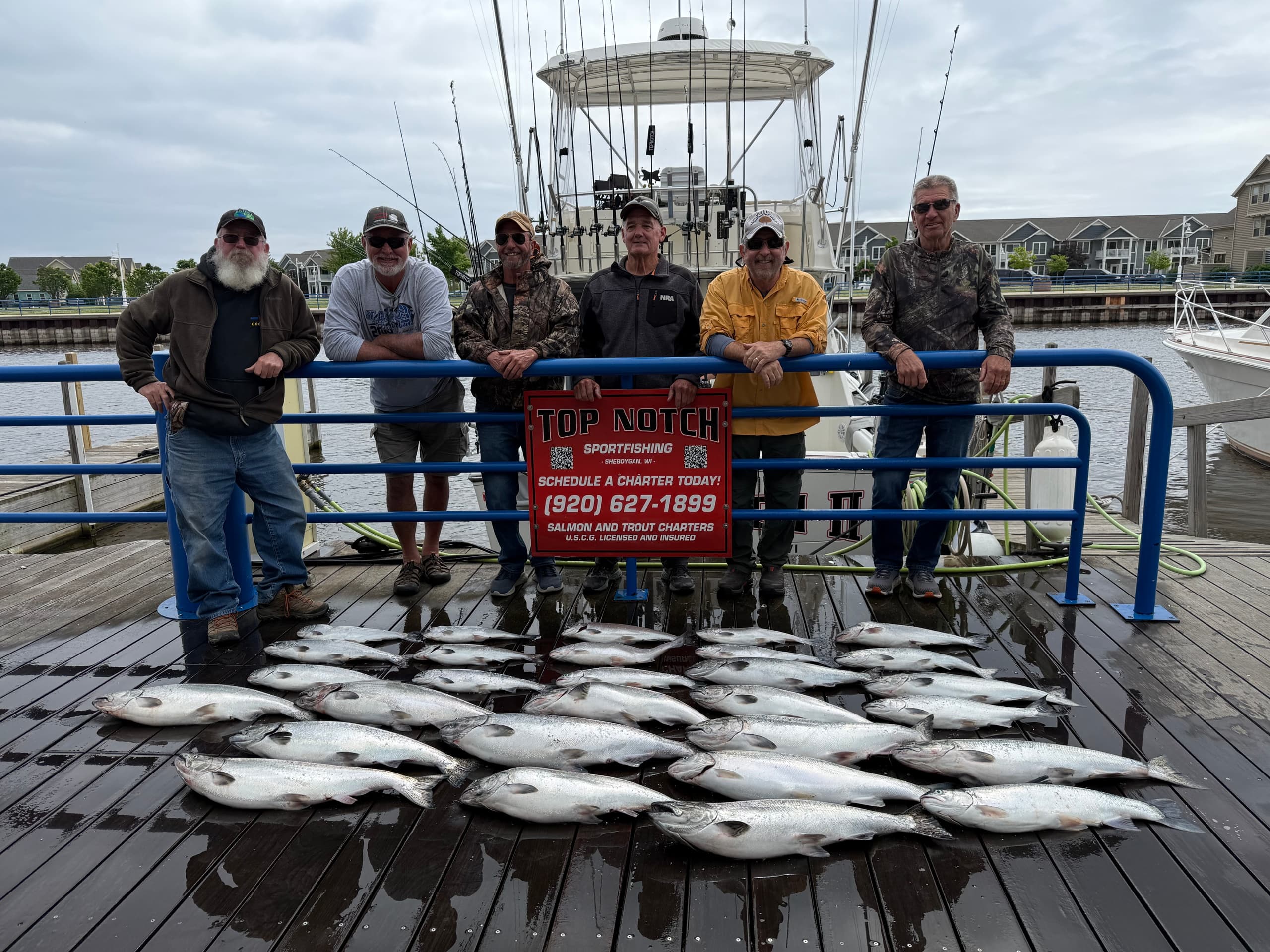 Charter anglers posing on dock with fresh trophy salmon catch