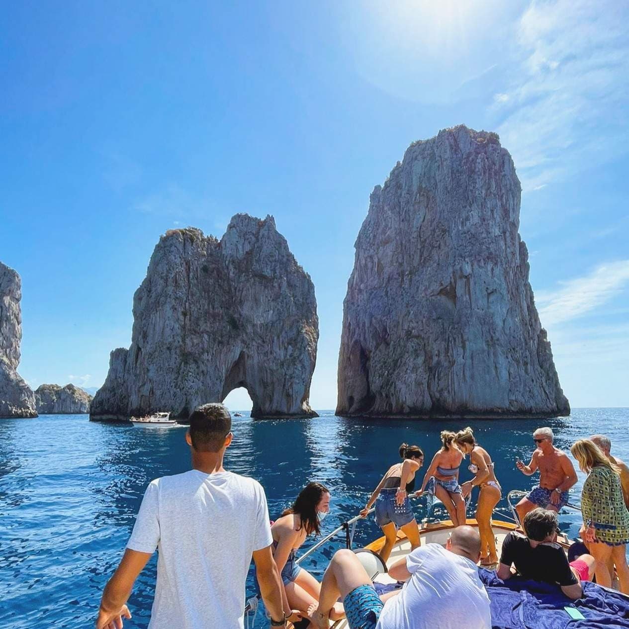Tourists on boat near Faraglioni sea stacks off Capri island
