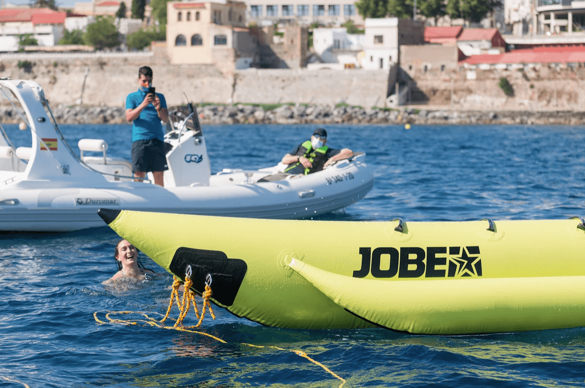 Banana boat and towing boat near harbor, group water tubing fun