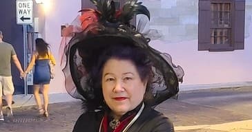 Woman wearing decorative hat on nighttime historic street