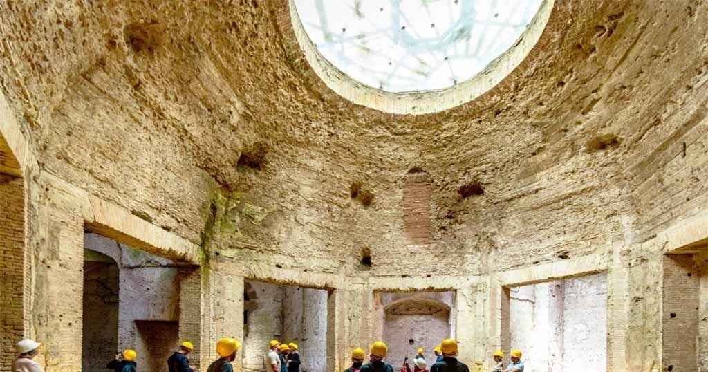 Visitors exploring ancient circular ruins chamber with oculus in Rome
