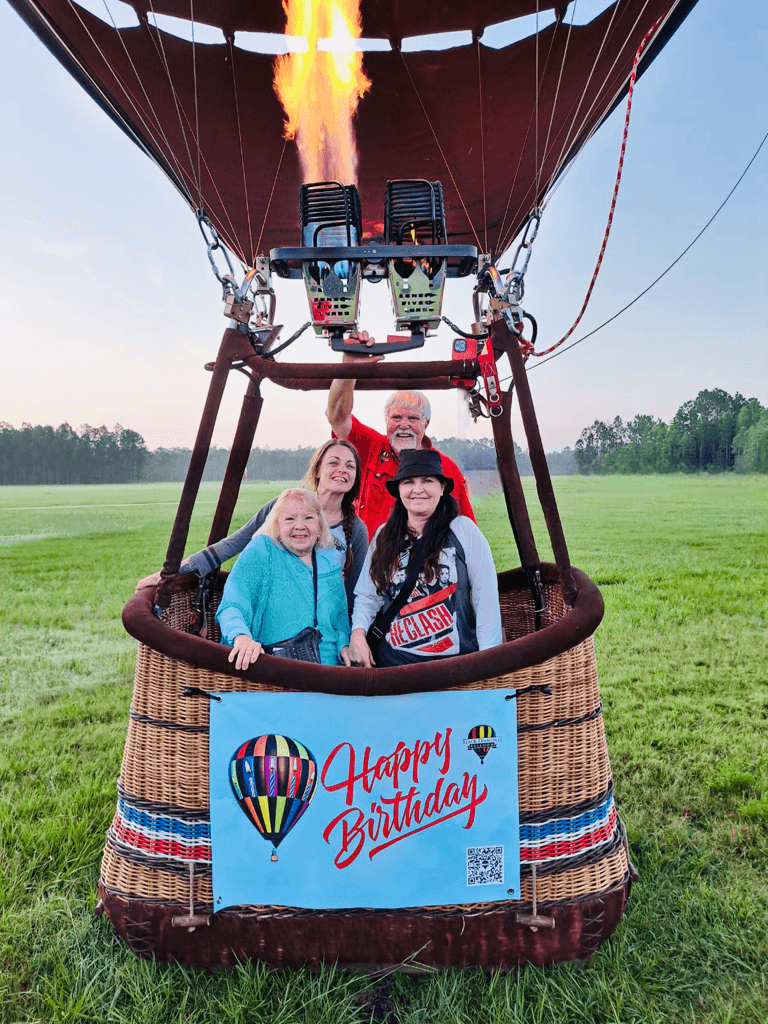 Hot air balloon basket with passengers and burner over meadow
