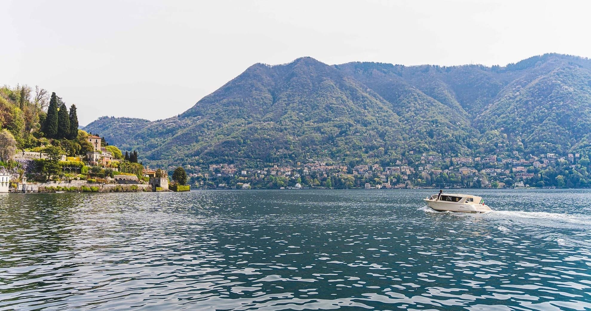 Wide Lake Como panorama with distant mountains and a small boat