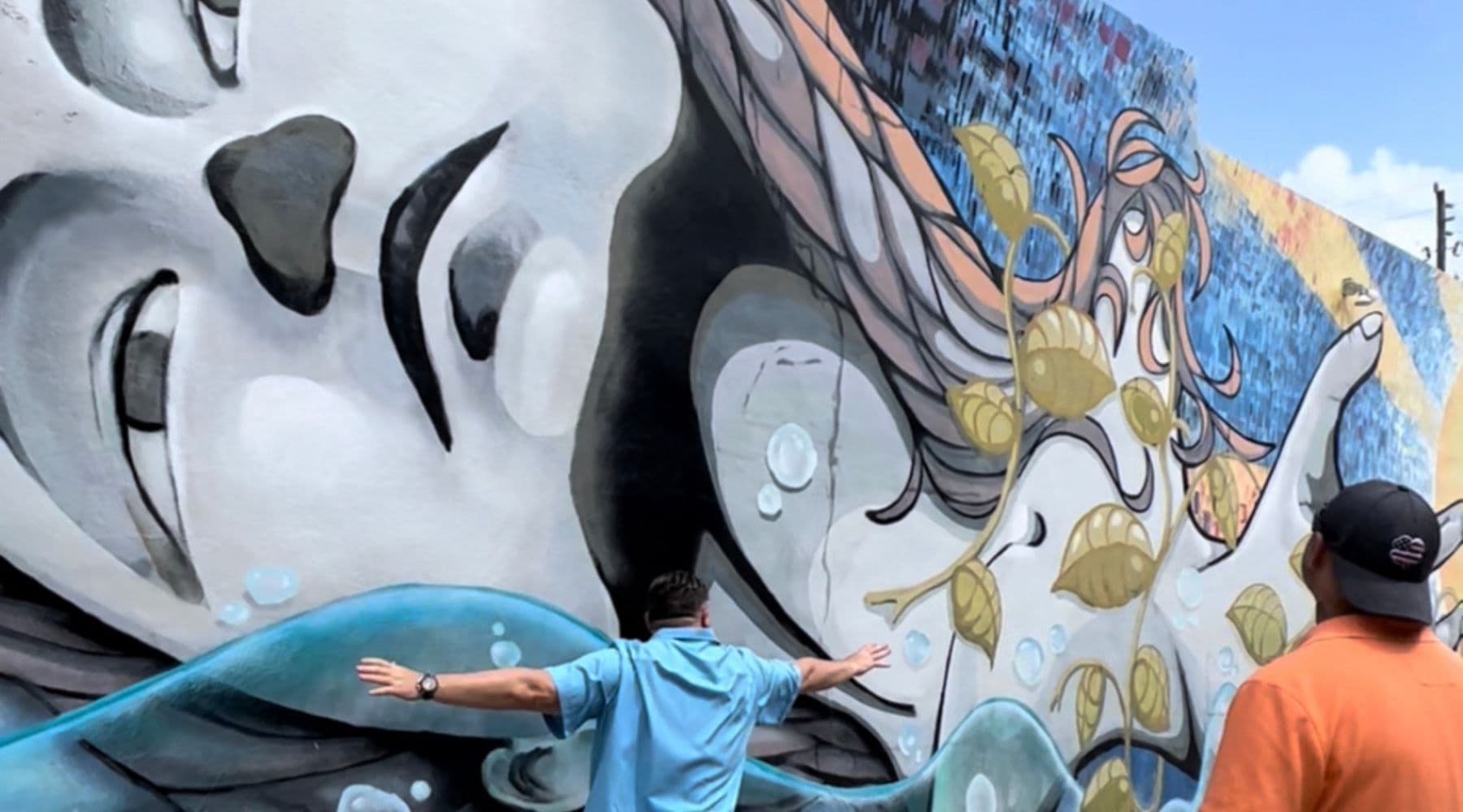 Large outdoor mural with visitors viewing street art in Hollywood