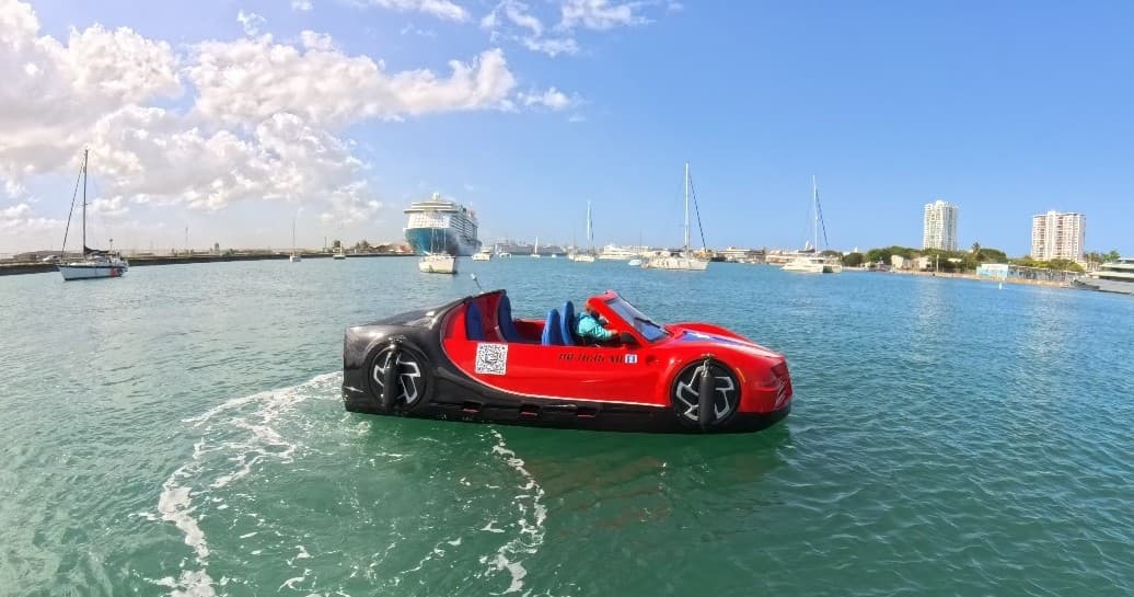 Red amphibious car on calm harbor water near marina piers