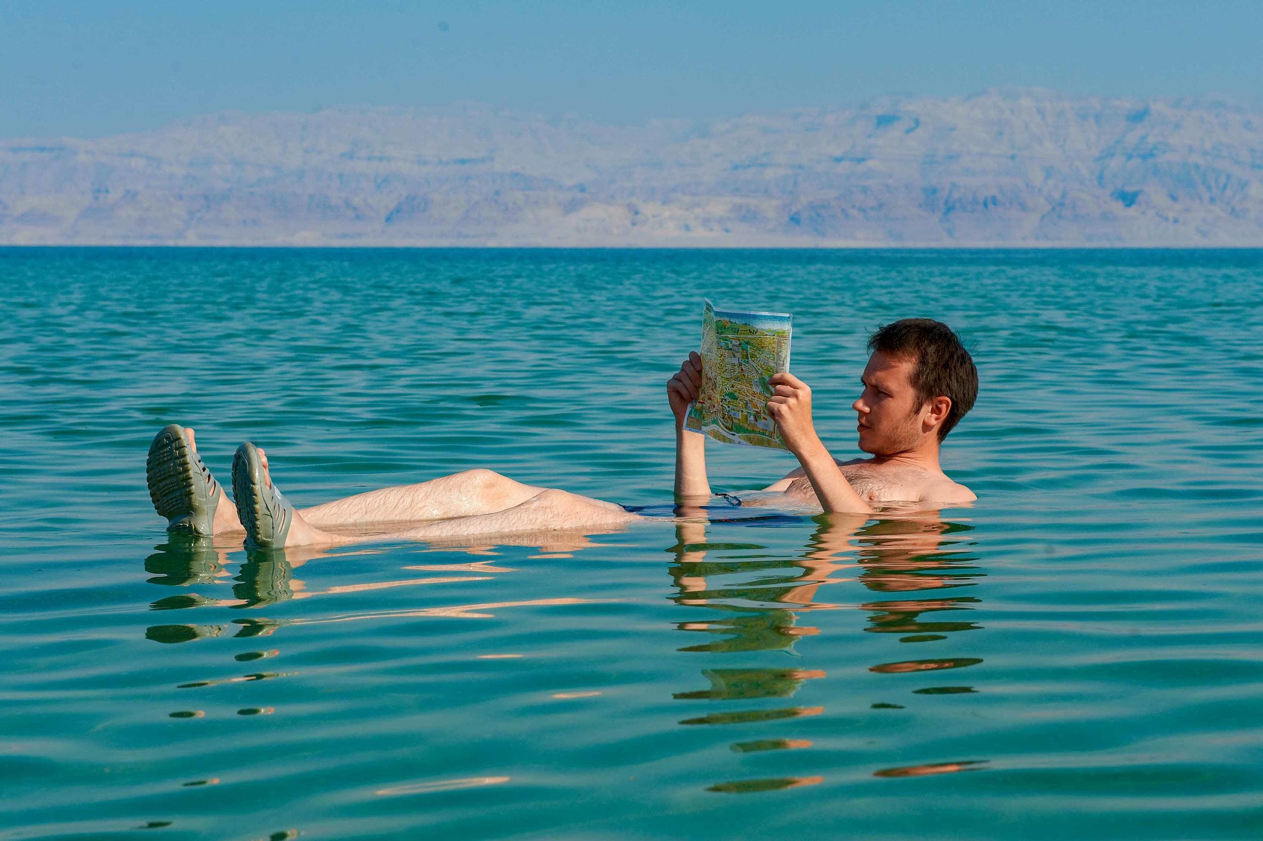 Person floating in salty lake with mountains in background