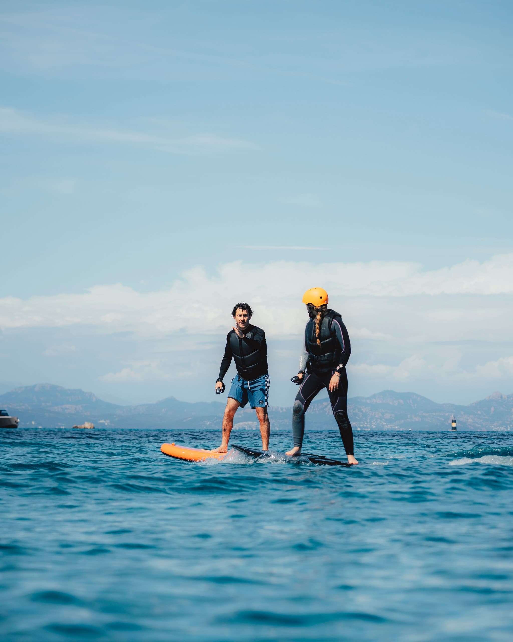 Two efoil riders gliding on calm sea with distant coastline