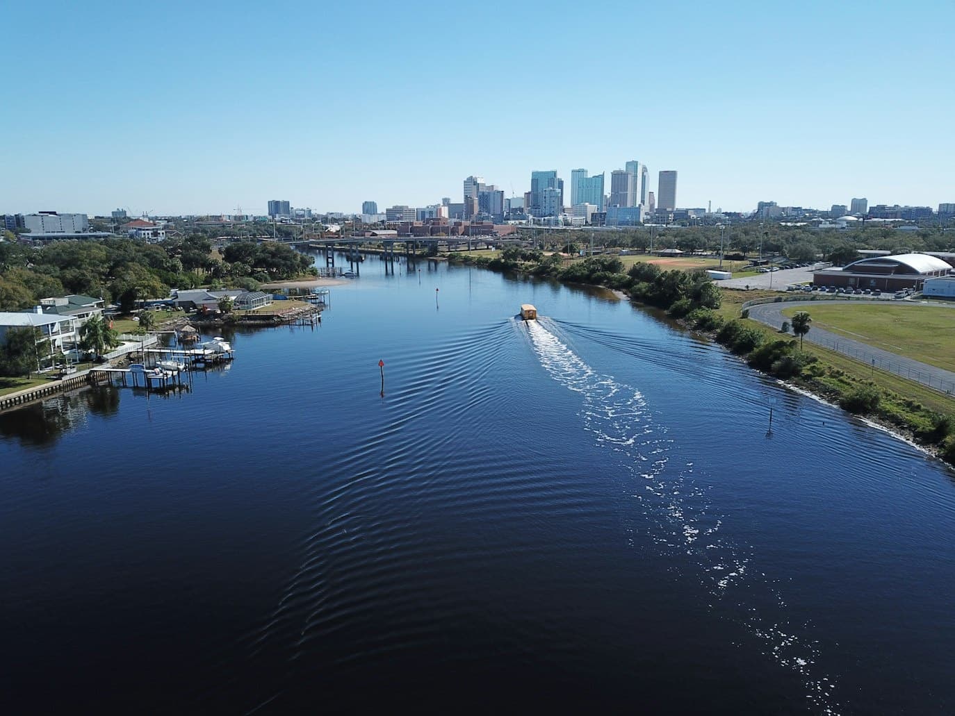 Small powerboat cruising a river toward Tampa skyline