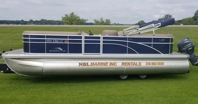 Silver pontoon boat on green lawn near lake, outdoor rental display