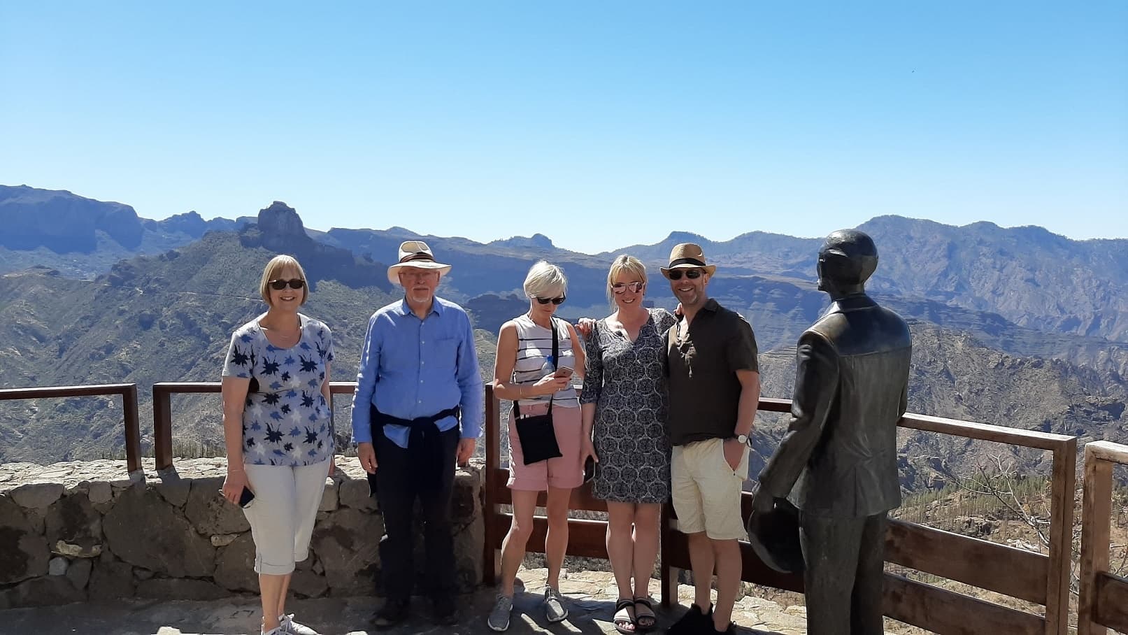 Group of hikers at scenic mountain lookout with bronze statue
