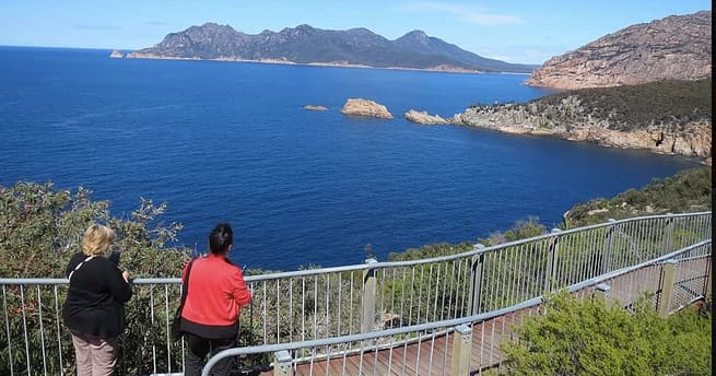 Coastal cliff lookout over turquoise ocean with visitors, scenic stop