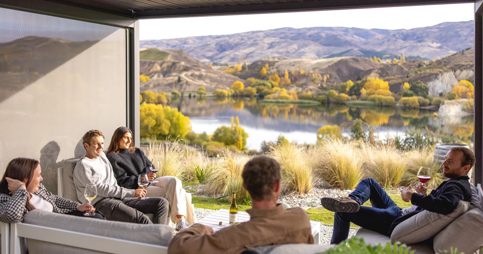 Friends relaxing on porch overlooking lake and rolling hills