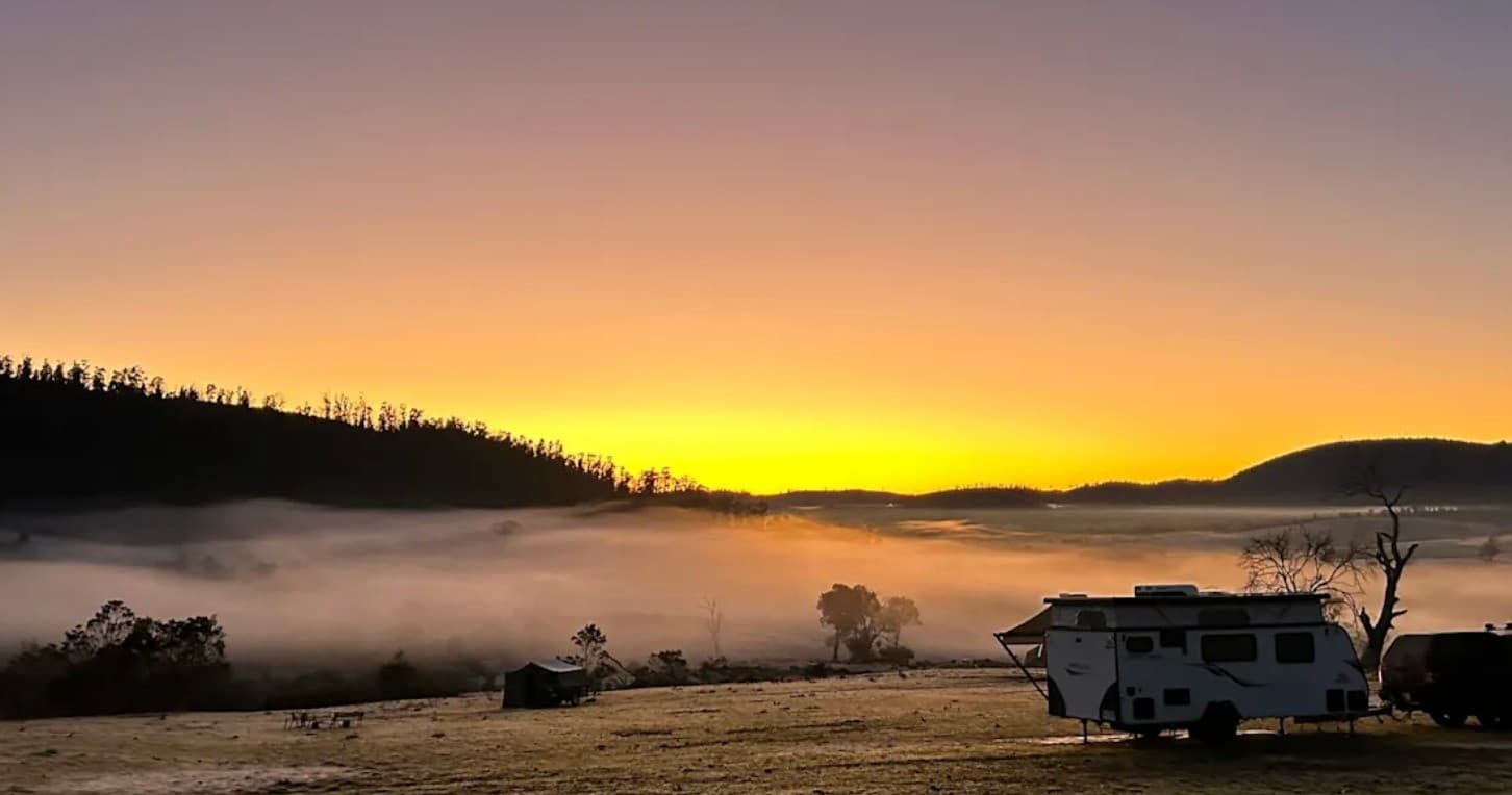 RV camping at misty sunrise in rolling hills, serene landscape