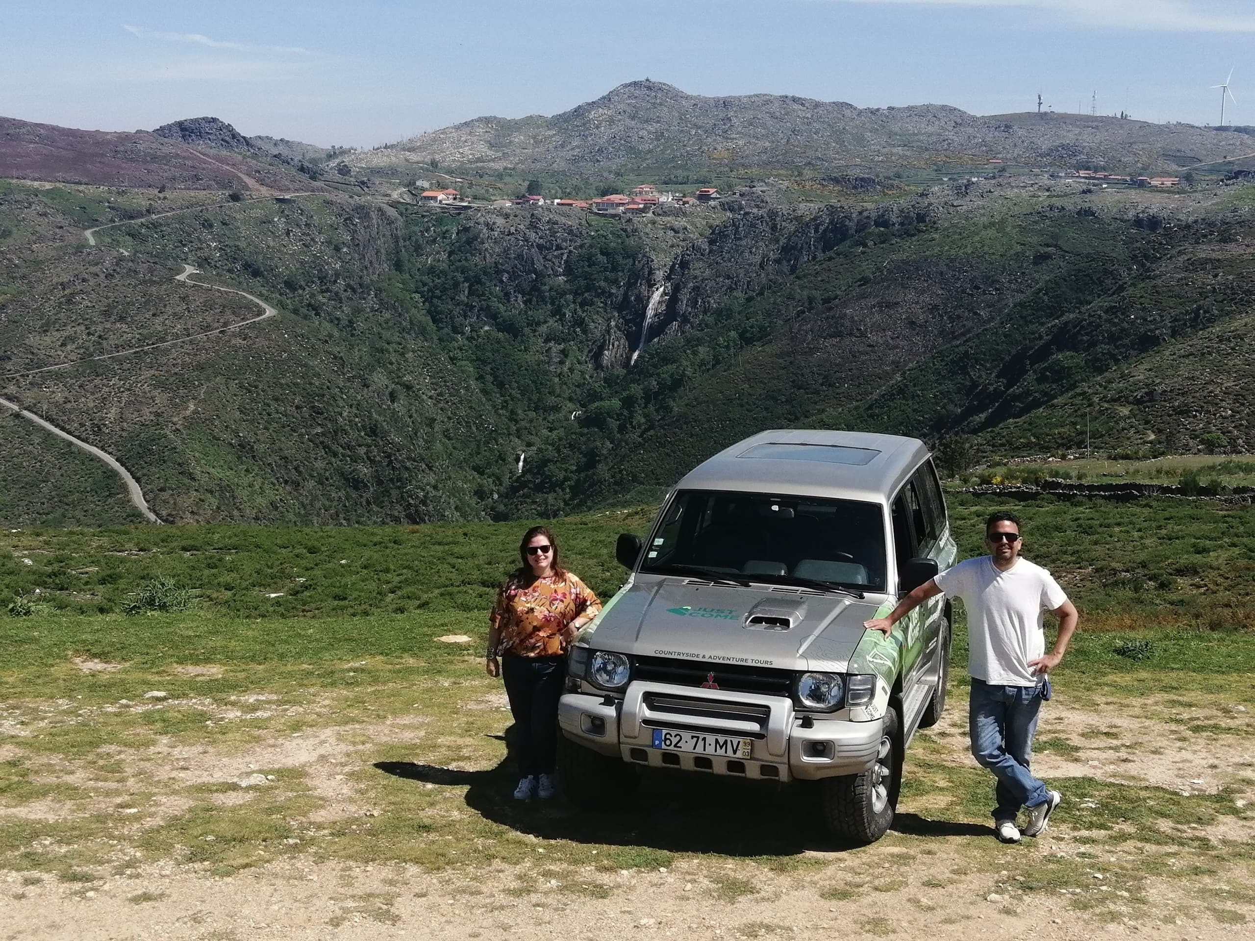 4x4 vehicle parked on grassy hill with sweeping valley panorama