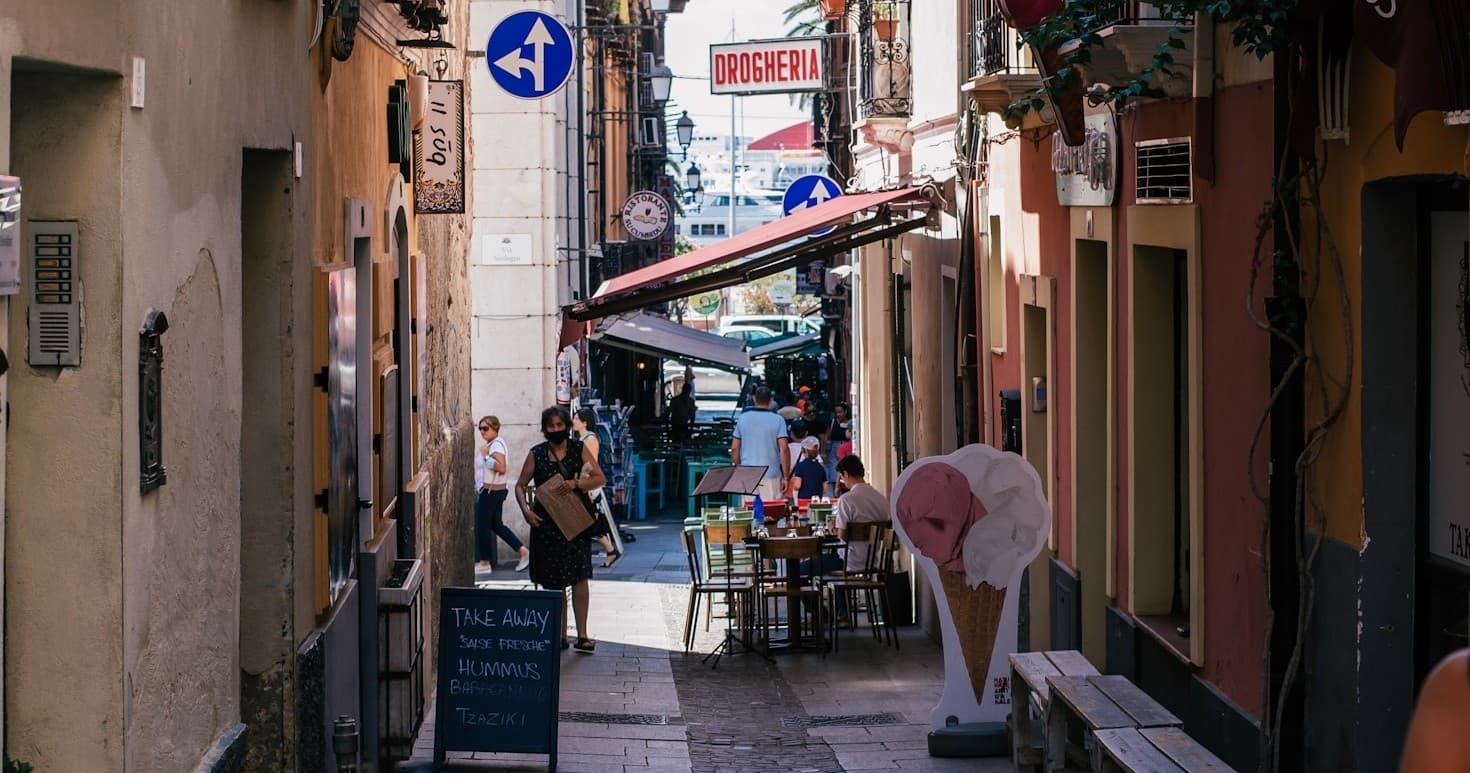 Tourists strolling a narrow Cagliari food alley, outdoor tasting
