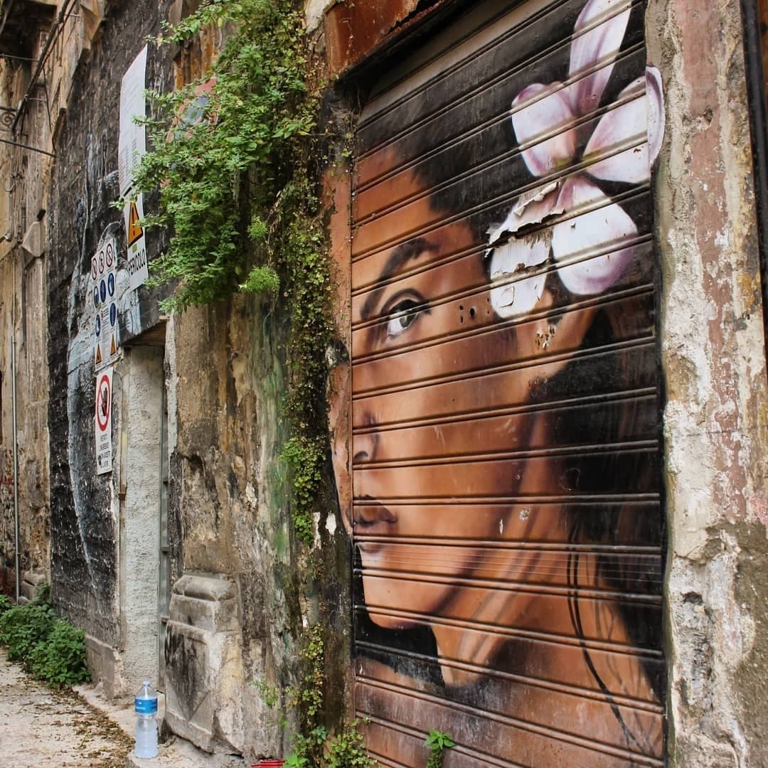 Large urban street-art portrait painted on a metal storefront shutter