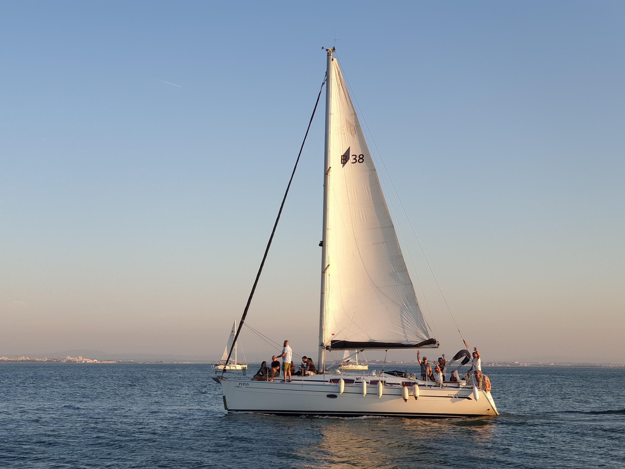 Sailboat cruising on open sea at golden hour, calm waters