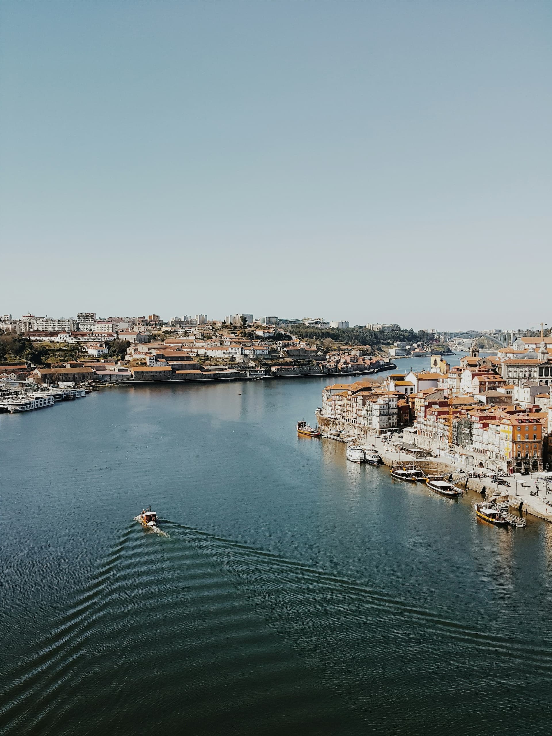 Aerial view of river and city, boat creating wake on water