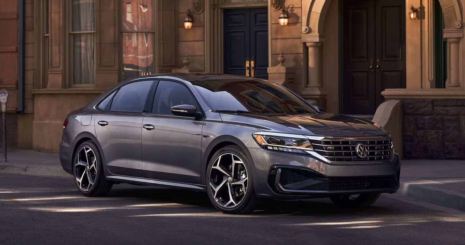 Gray luxury sedan parked on city street by historic building