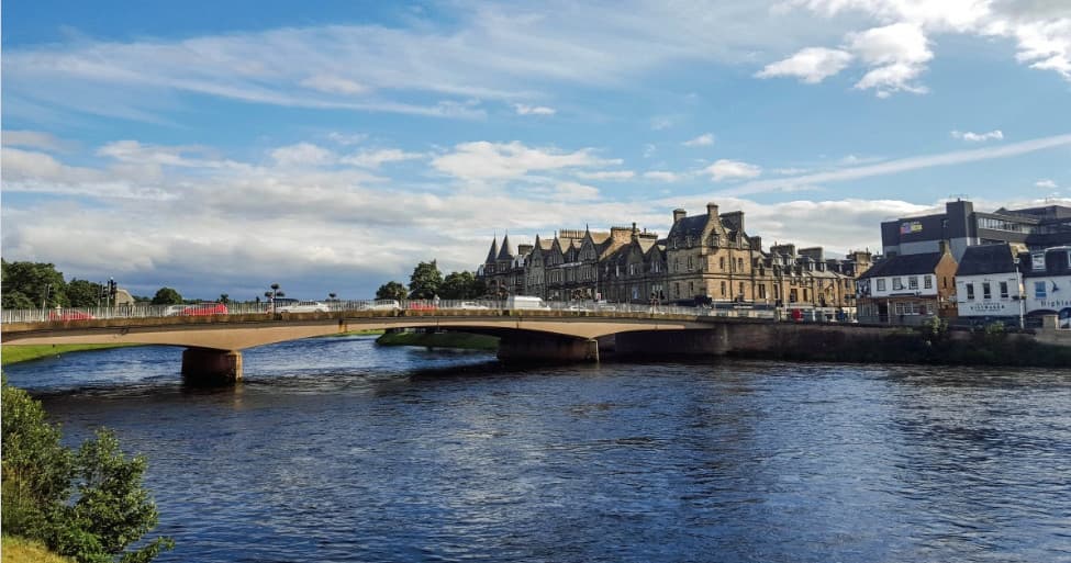 Guided walking tour group along riverside promenade with boats nearby