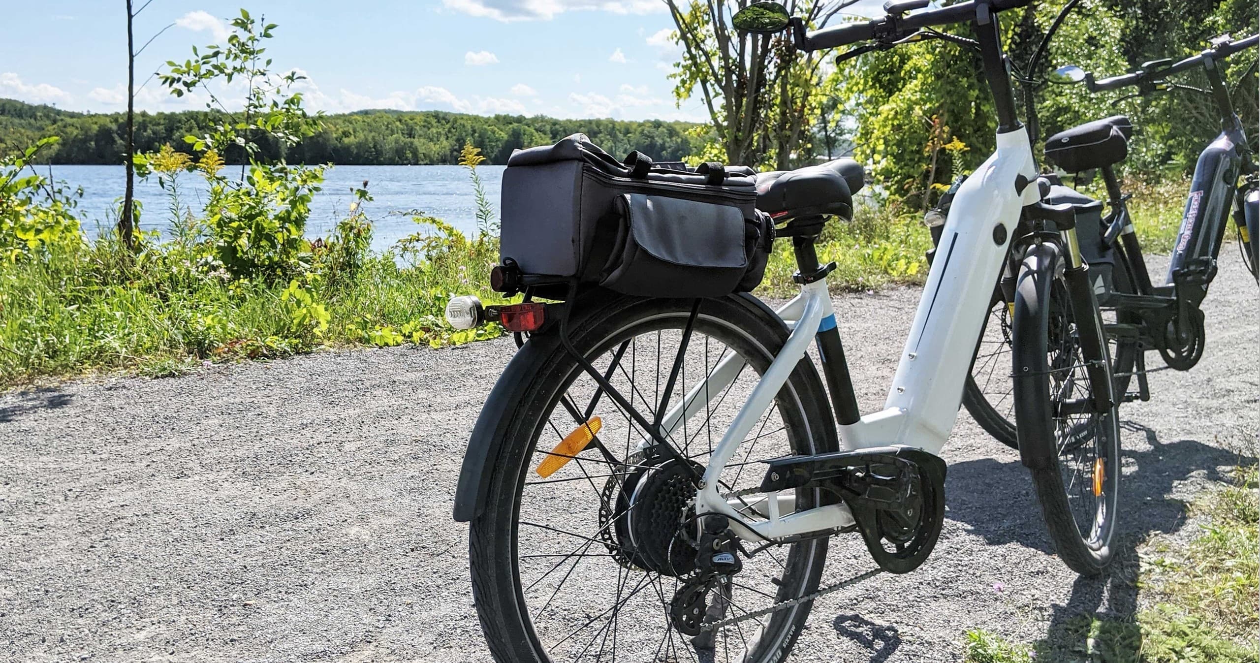 White electric bike parked by lakeside trail, touring gear