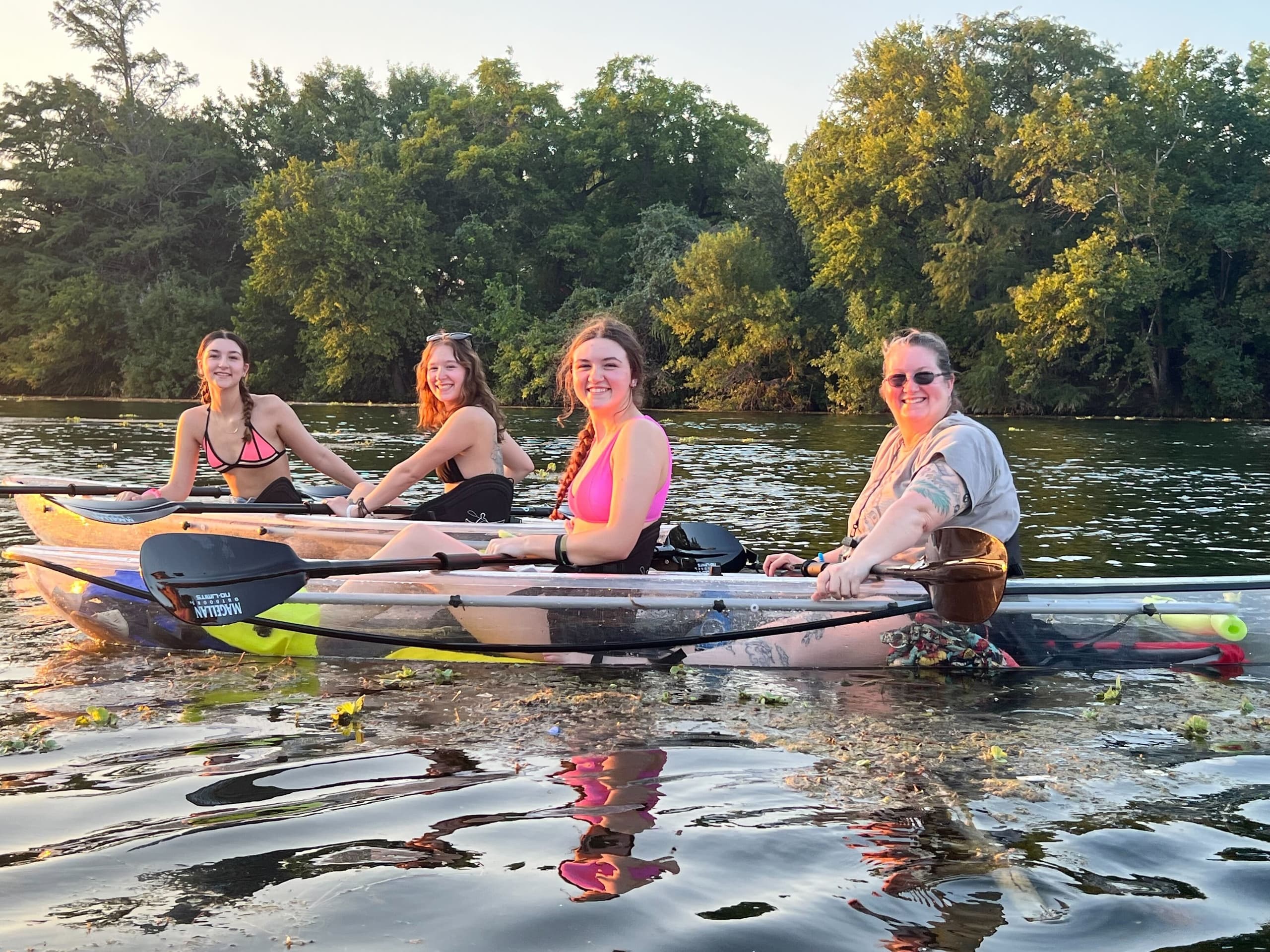 Group of four kayaking on Austin lake at golden hour reflections