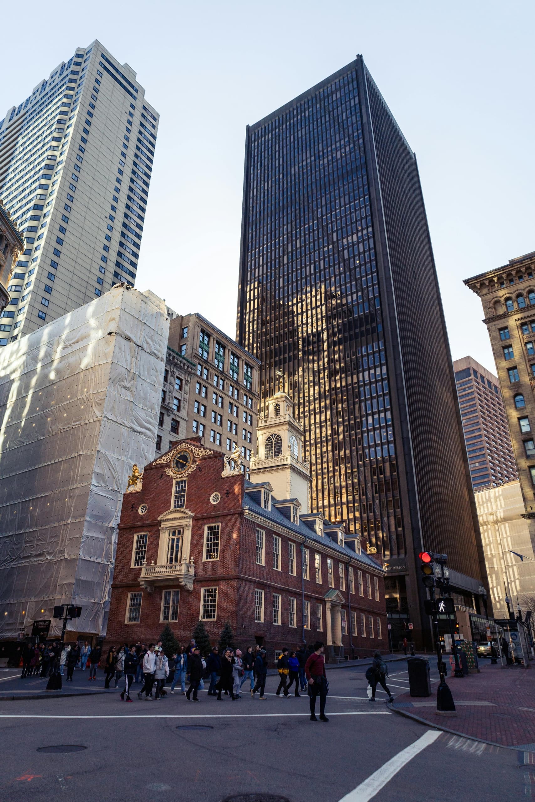 Pedestrians on Boston street with historic brick house and skyscrapers