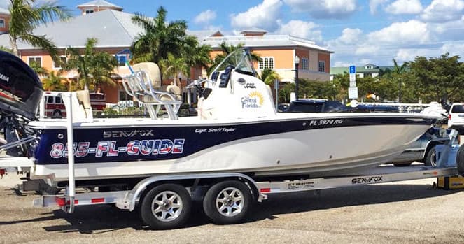 Fishing boat on trailer at marina near palm trees and docks