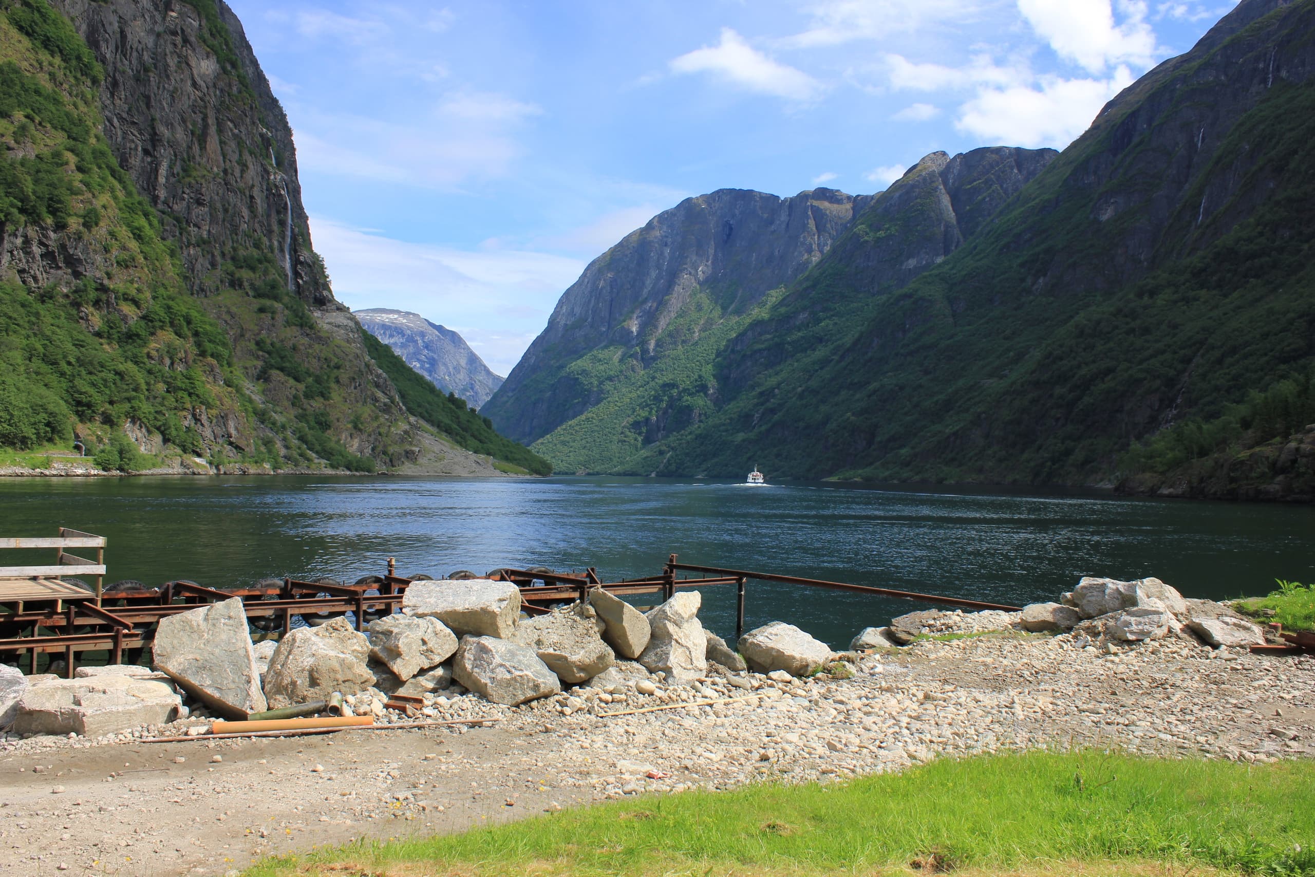 Gravel shore and fjord framed by steep green cliffs, tranquil view