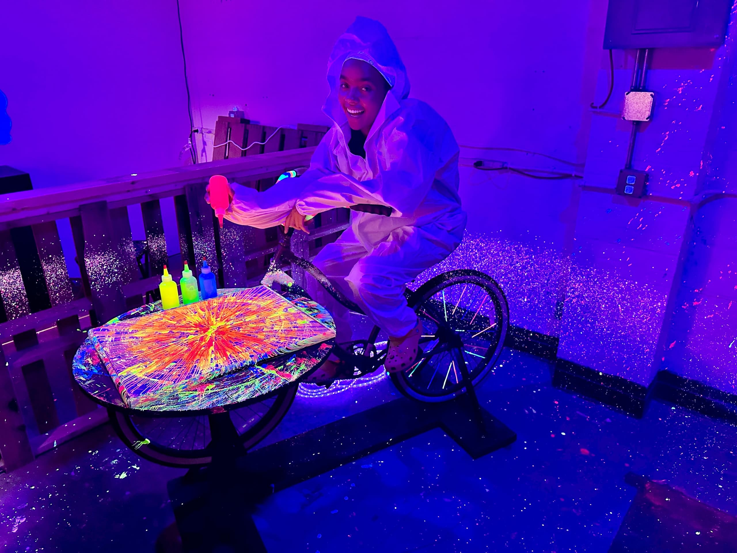 Person cycling with neon paint under blacklight in studio