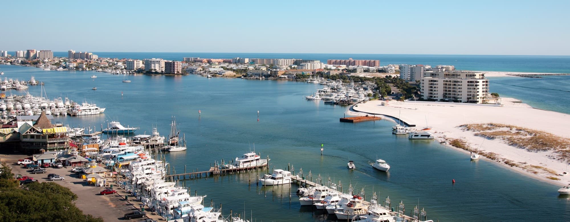 Coastal marina panorama with boats and sandy barrier island