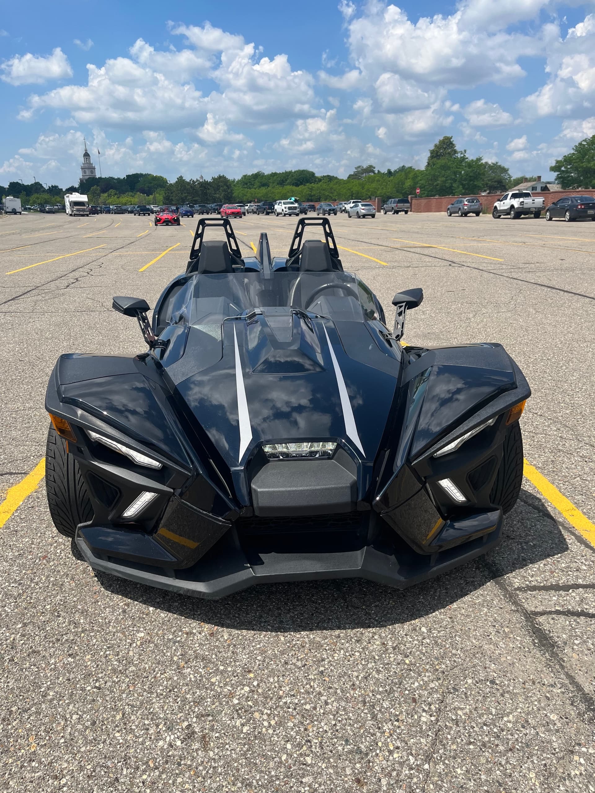 Front view black Slingshot roadster parked under blue sky
