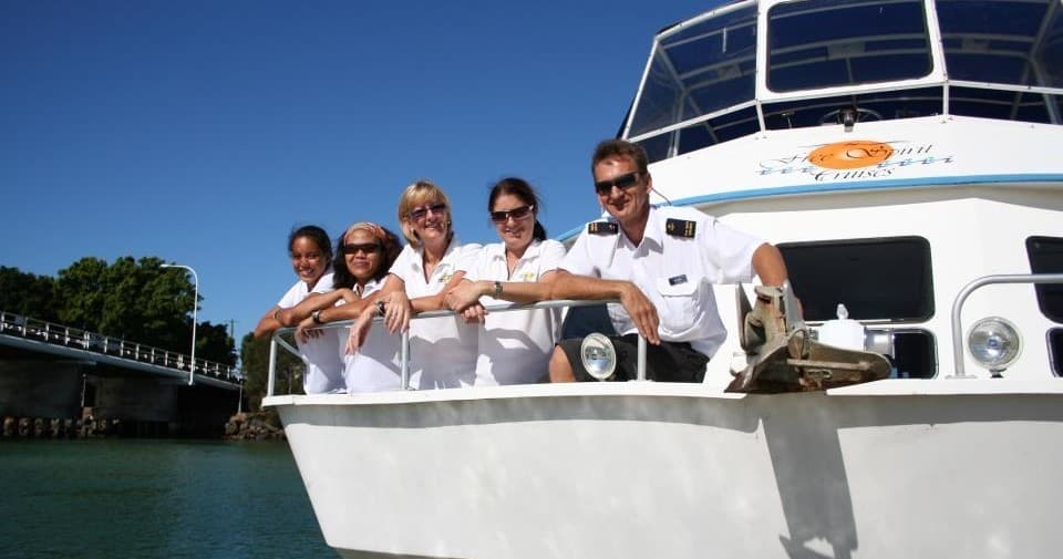 Tour boat crew smiling on bow during sunny harbor sightseeing