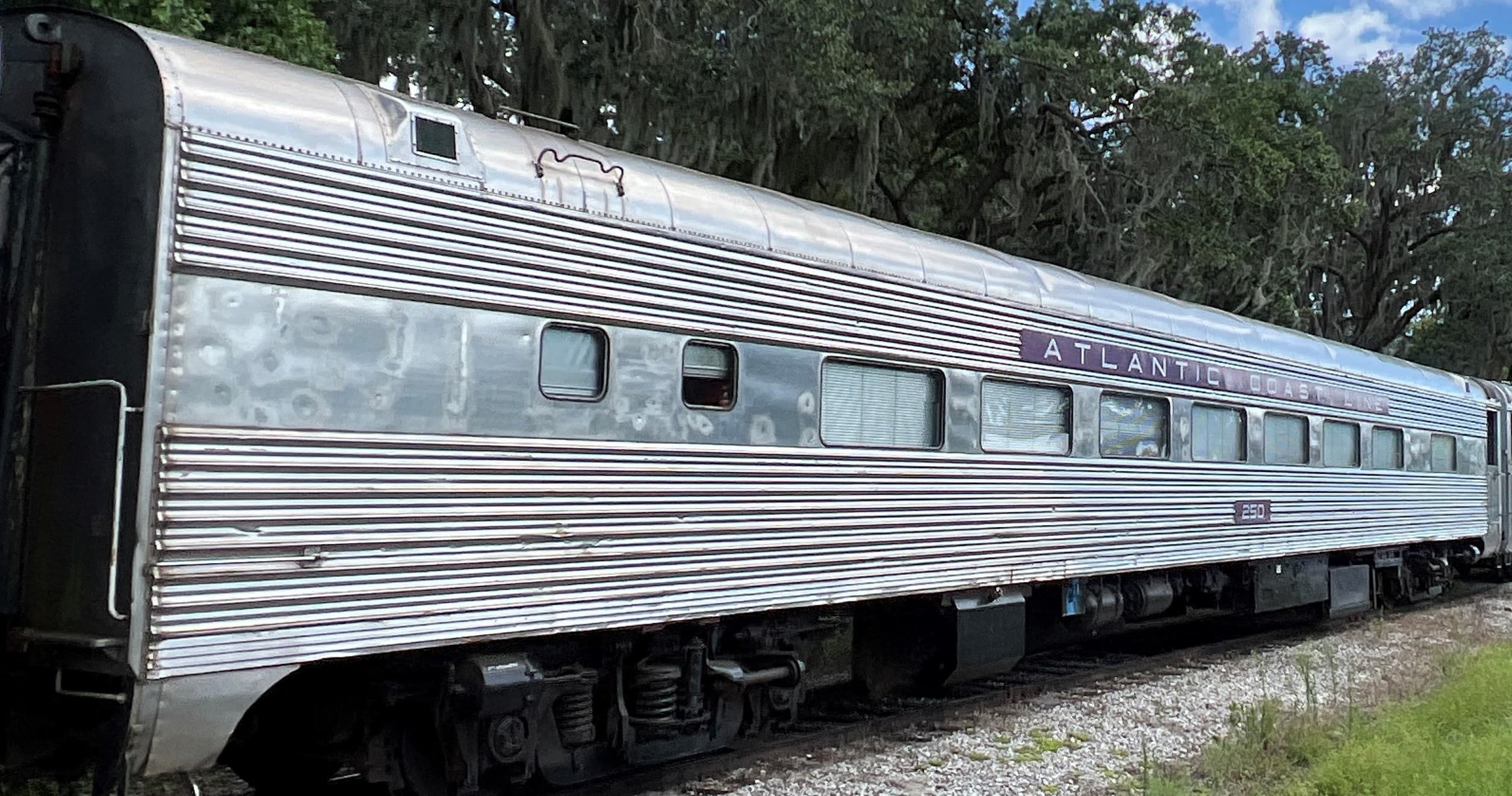 Stainless steel passenger car resting on tracks at outdoor museum