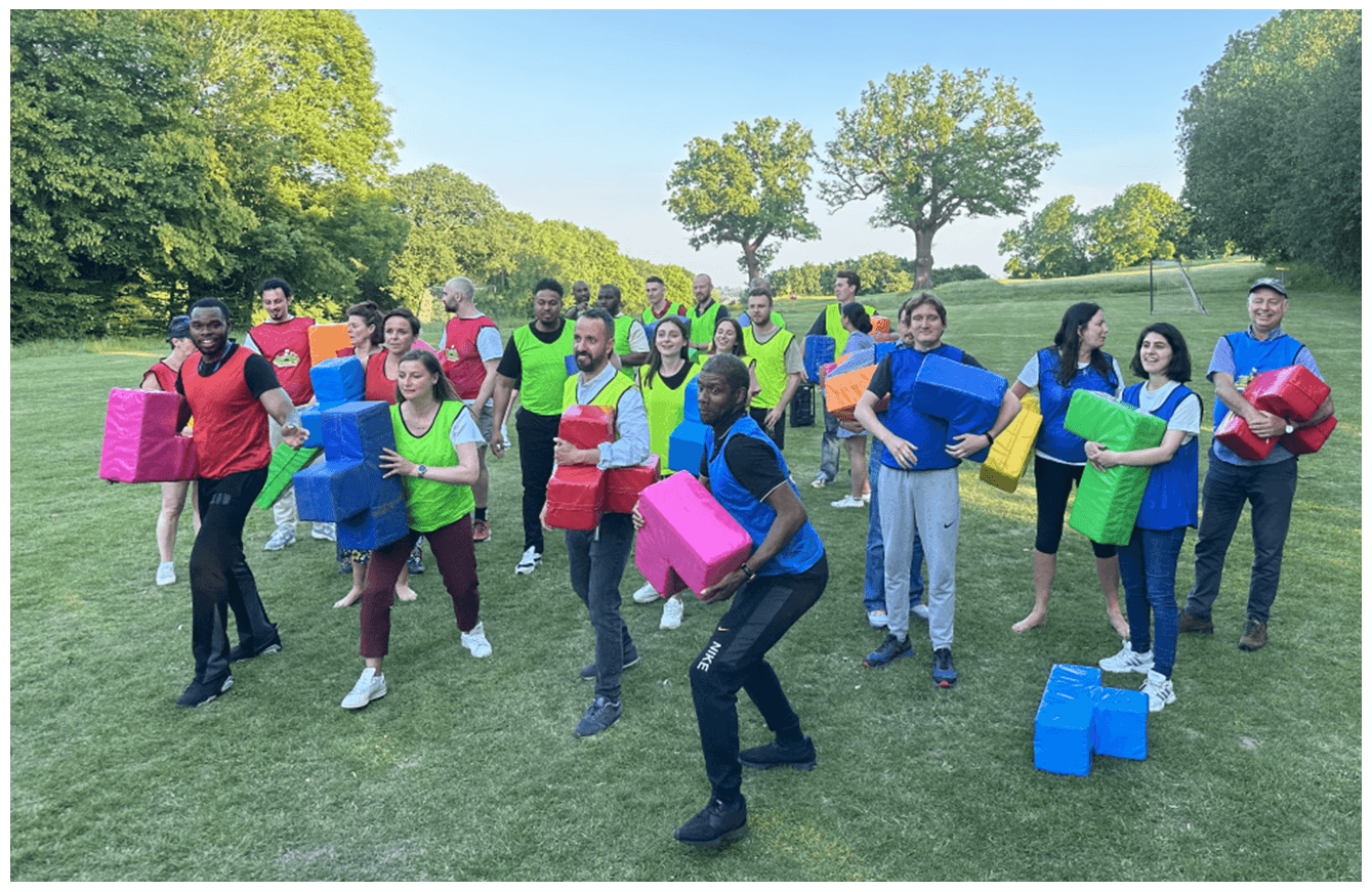 Large team building group in high-vis vests on green park lawn