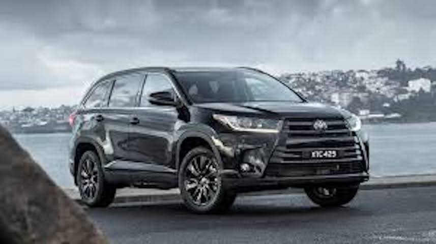 SUV driving along rugged coastal road with ocean backdrop