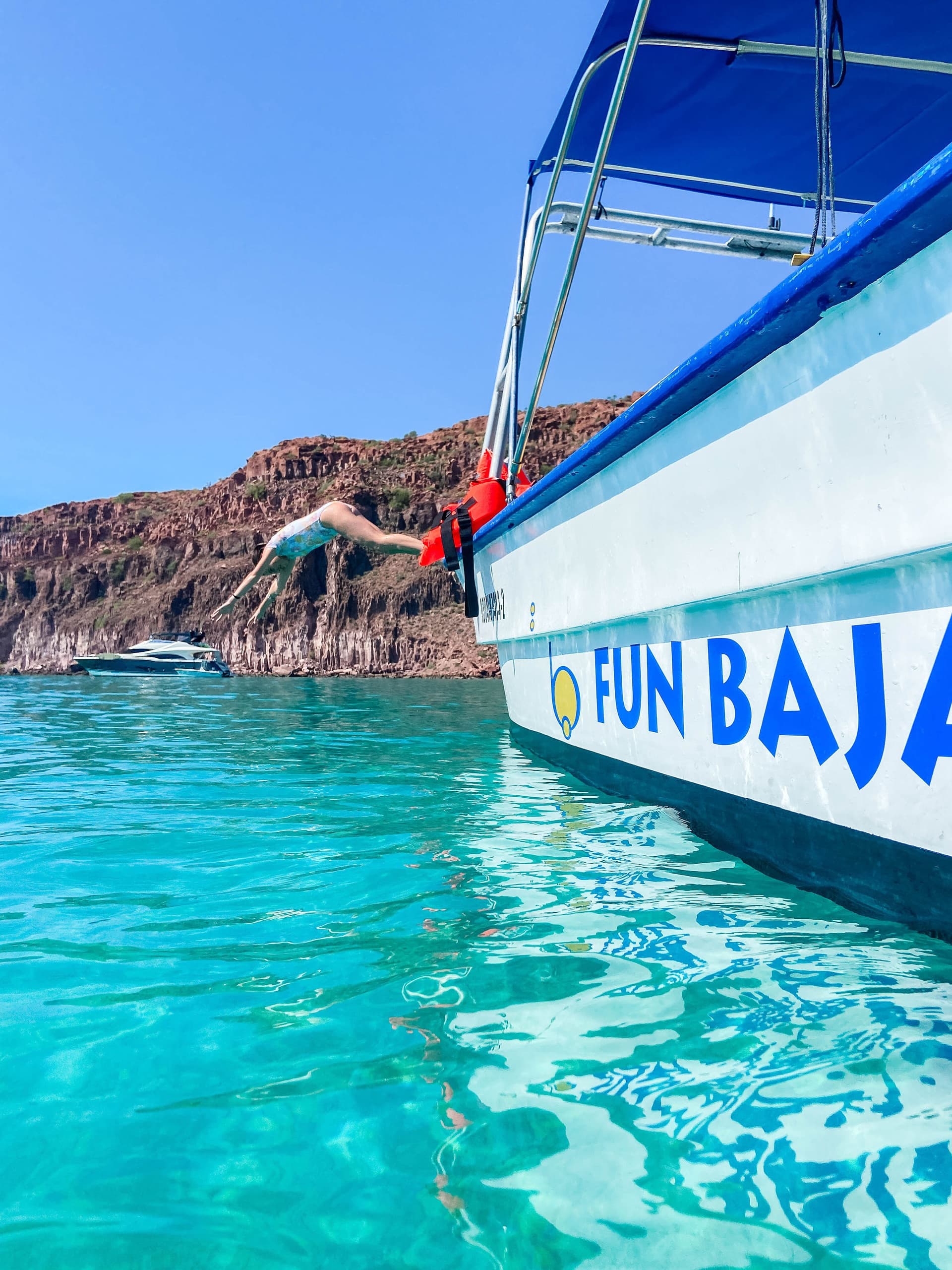 Tour boat Fun Baja on turquoise waters near rocky shore