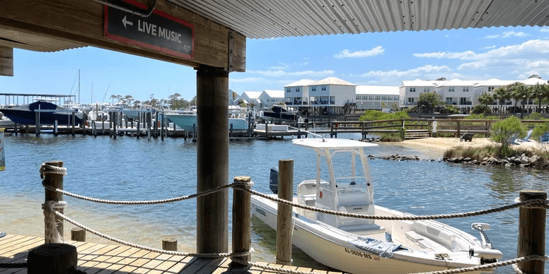 Small boat docked at marina pier with clear bay and condos