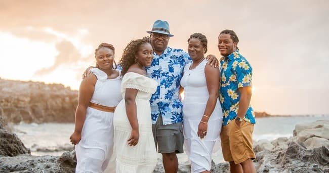 Family portrait on rocky shoreline with ocean and soft sunset