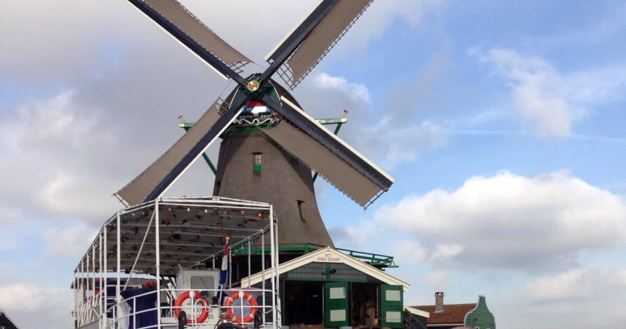 Traditional Dutch windmill framed beside river and cruise deck