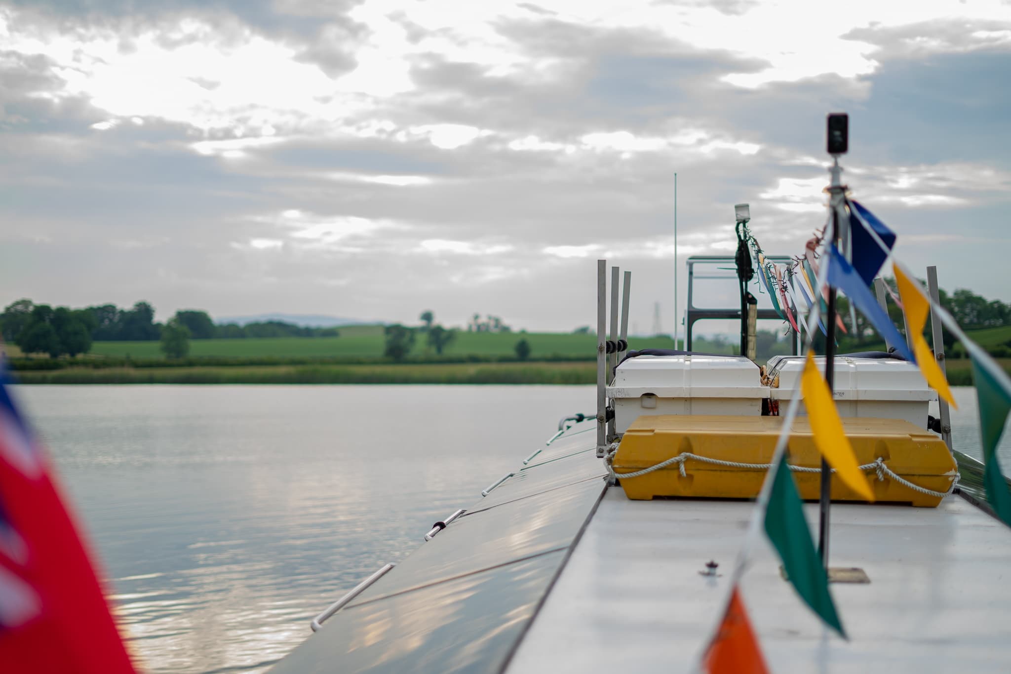 Boat deck with colorful signal flags overlooking calm river landscape