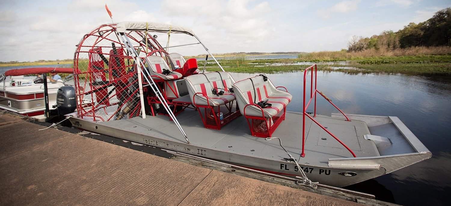 Parked airboat at marsh launch with calm river panorama