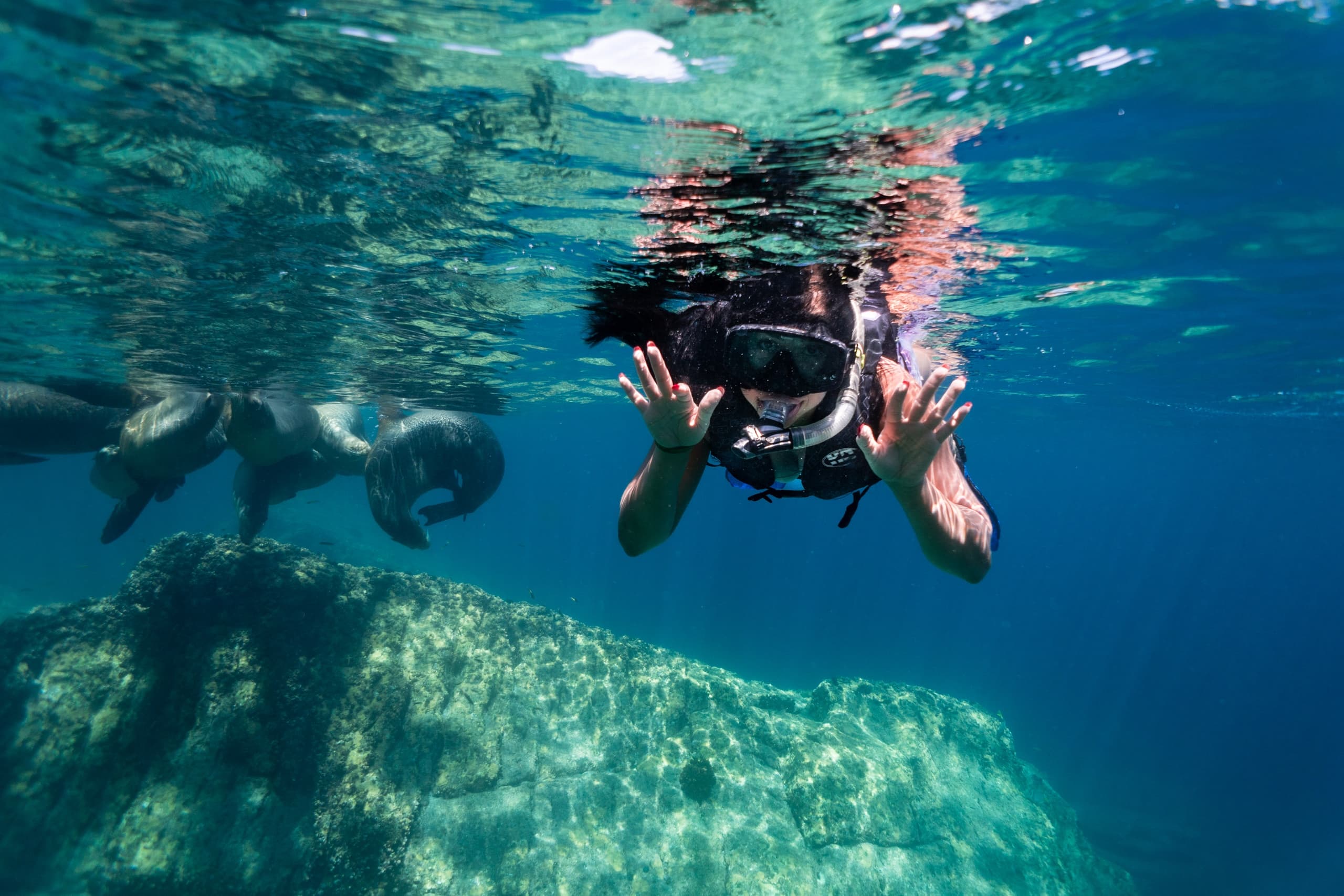 Two snorkelers exploring shallow reef with sunlight reflections
