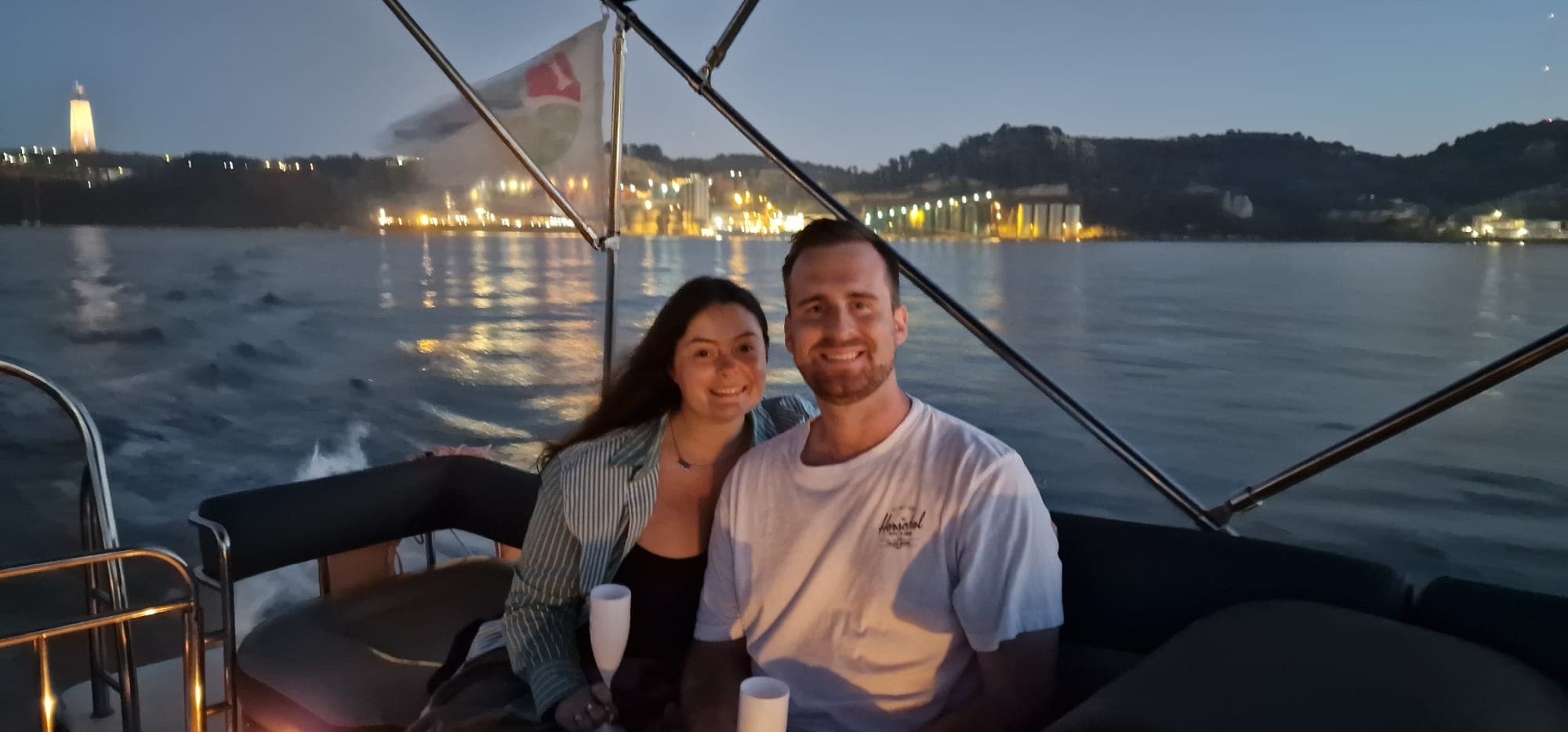 Couple enjoying evening boat ride with city lights on water