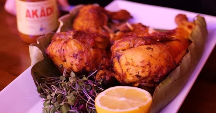 Roasted chicken with lemon and herbs on tray, moody restaurant plating