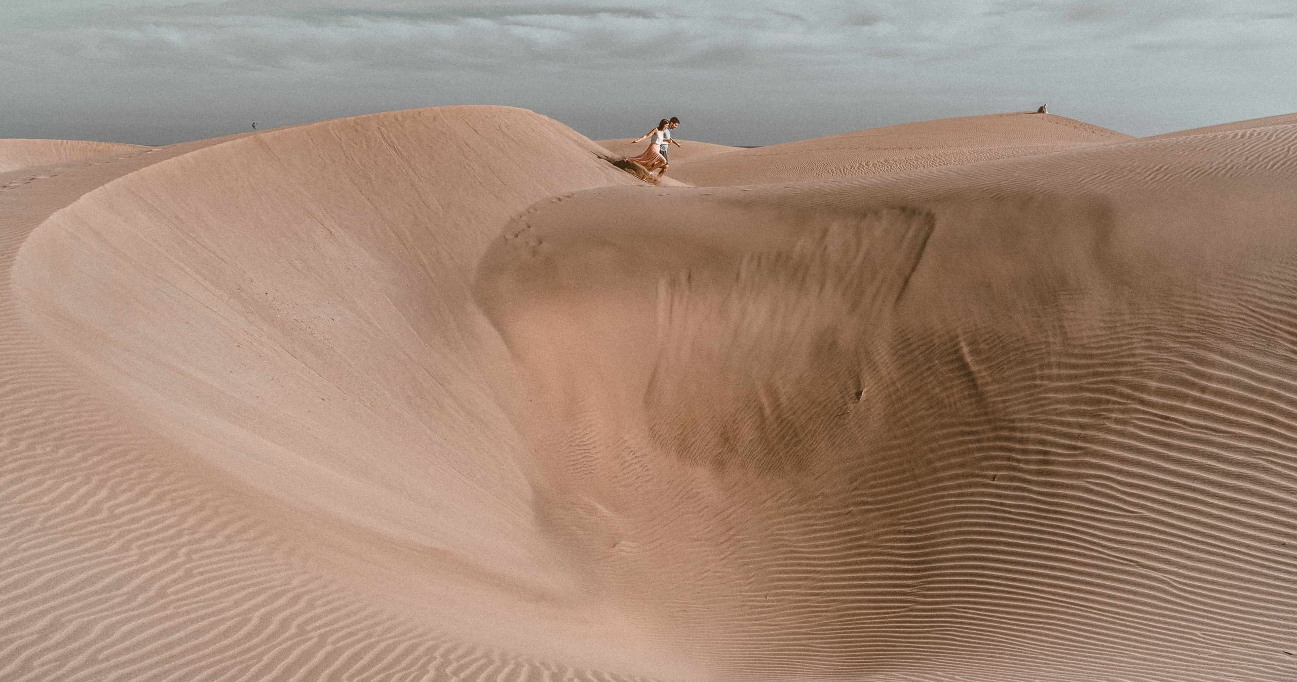 Solitary hiker exploring sweeping sand dunes and desert landscape