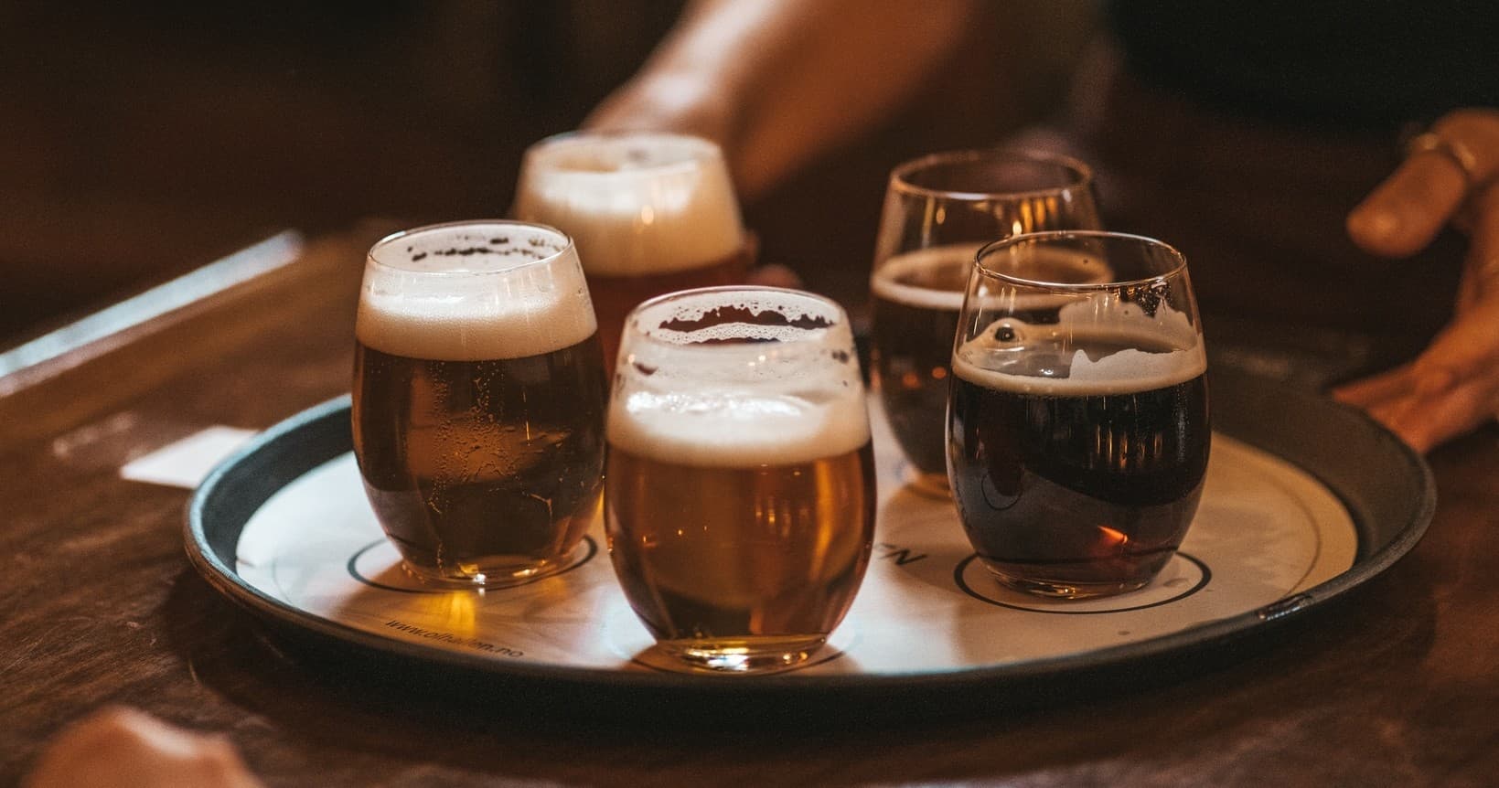 Flight of craft beers on wooden tray at cozy pub tasting